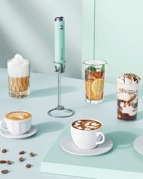 Rechargeable Milk Frother Holder And Whisk Rod In Silver displayed among coffee drinks and accessories on a pastel surface