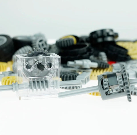 Close-up of Gear Builder Bulk Kit for Brick Creations, featuring clear gearbox, gears, axles, and universal joints on a white background.