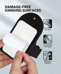 Hands holding adhesive strip of Beefy Heavy Duty Broom Holder Wall Mount Set Of 4 Black Metal Bracket showing damage-free features.