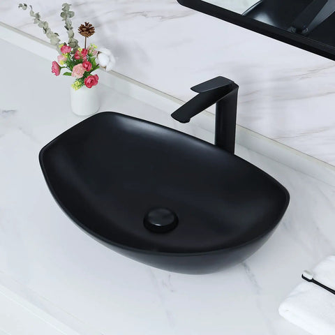 Black ceramic vessel sink on countertop with faucet and flowers on the side, different from White Ceramic Vessel Sink 19 By 14.5 Inch With Pop Up Drain Above Counter Bathroom Sink Modern Vessel Bowl For Vanity Durable Glazed Ceramic Finish Countertop Sink For Stylish Homes