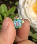 Score These Hella Rad Lampwork Glass Round Spacer Beads With Big Center Holes Perfect For DIY Jewelry Making Kicking Up Your Bracelet And Necklace Crafting Vibes Today - close-up of blue and floral glass bead.