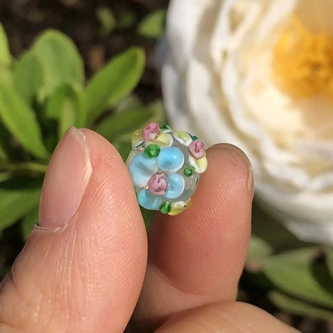 Score These Hella Rad Lampwork Glass Round Spacer Beads With Big Center Holes Perfect For DIY Jewelry Making Kicking Up Your Bracelet And Necklace Crafting Vibes Today - close-up of blue and floral glass bead.