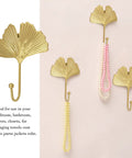 Ginkgo Leaf Wall Hooks Four Piece Iron Gold Key Holder And Hat Hanger, displayed with necklaces on neutral wall