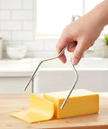 Heavy Duty Stainless Steel Cheese Slicer Wire And Y Type Cutter With Twist Lock, slicing yellow cheese at kitchen counter.