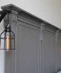 Black Wooden Triangle Wall Mount Brackets for Sconce Lighting above gray paneling with pendant lights
