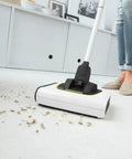 Cordless Electric Floor Sweeper Broom With Whisper Quiet Rollers For Hardwood Vinyl Tile And Rugs Lightweight Automatic Sweeper Machine For Pet Fur Hair Dust And Household Mess White cleaning debris on a light surface.