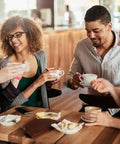 Four friends enjoying coffee together at a cafe, sharing conversation and laughter around a small table.