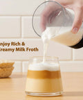 Pouring milk froth into coffee glass, showcasing Handheld Cold Foam Frother For Coffee Battery Powered With Two AA One Button Operation