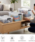 Clear Plastic Storage Bins With Snap On Lids For Home Office Organization Stackable Crates BPA Free Non Toxic Craft And Tool Organizer 13.7 Quart 12 Pack, organized on a coffee table.