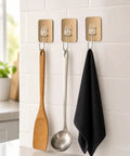 Six Pack Tough Grip Adhesive Wall Hooks Offering No Sweat No Drill Install slick gold square plate with clear hooks holding kitchen utensils.