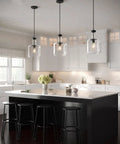 Latrobe Collection 1-Light Clear Glass Coastal Pendant Light in Matte Black above kitchen island with bottle-shaped shades