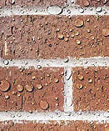 The Real Deal Deep Penetrating Siloxane Masonry Sealer For Brick Concrete And Stucco Hydrophobic Waterproof Barrier Coating With Extended All Weather Defense visible on wet brick wall with water beads.