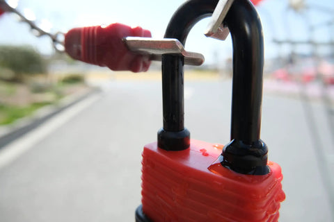 Colored Waterproof Padlocks Set With Keyed Alike Locks, red lock in focus, laminated steel construction, in outdoor setting.