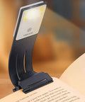 Clip On Bookmark Reading Light For Books In Bed With Adjustable Brightness Levels Soft Eye Friendly LED Built In USB Charge Ideal For Readers And Kids clipped onto an open book.