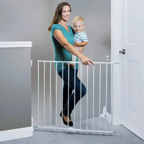 Woman holding child beside Essential Stairway and Walkway Baby Gate for Stairs and Doorways, Hardware Mounted, 30 Inch Tall, White