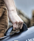Close-up of a person holding the handle of a 60,000 BTU Portable Propane Forced Air Heater With Quiet QBT Technology, shown outdoors.