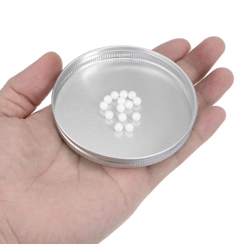 Ceramic bearing balls, 5 mm diameter, zirconia oxide, white; 28pcs in a metal lid held in hand (close-up).