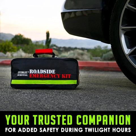 Everlit roadside emergency kit bag, black with neon green stripe and red handle, beside car tire.