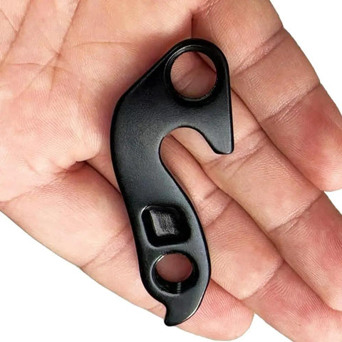 Hand holding Beefy Rear Derailleur Hanger 11 Replacement for select road and gravel bikes, CNC machined aluminum with anodized finish.
