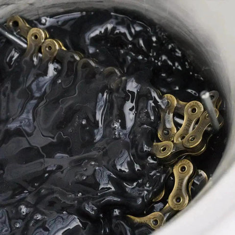 Close-up of Bike Chain Wax Kit For All Conditions Keeps Your Drivetrain Slick No More Grease Marks Or Messy Cleaning Delivers Smooth Shifts And Peak Efficiency On Every Ride One Pound Bag showing chain in wax.