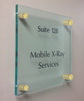 Premium Gold Standoff Screws For Acrylic Signs holding glass signage labeled Suite 128 Mobile X-Ray Services on a wall.