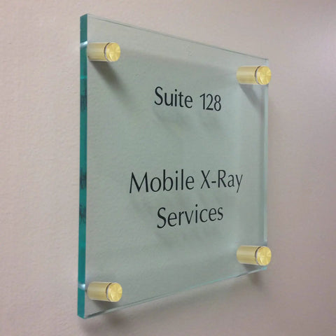Premium Gold Standoff Screws For Acrylic Signs holding glass signage labeled Suite 128 Mobile X-Ray Services on a wall.