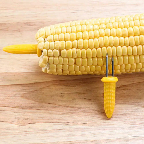10 Piece Stainless Steel Corn Holders Set For Corn On The Cob Twin Prong Skewers shown holding corn on wooden surface