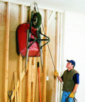 Man using Overhead Garage Hoist System For Bikes And Ladders Single Point Lift 45lb Capacity Self Leveling with wheelbarrow