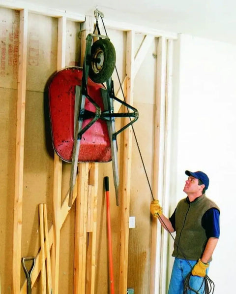 Man using Overhead Garage Hoist System For Bikes And Ladders Single Point Lift 45lb Capacity Self Leveling with wheelbarrow