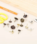 Fifty Pack Vintage Flower Head Upholstery Tacks Iron Metal Furniture Repair Nails Decorative Crafting Supplies For Couch Chairs Diy Home Projects Gold White Finish Hella Durable Top Notch Quality For Easy Fix Ups Crib Refresh And Quick Nail Setup, assorted decorative tacks on a table.