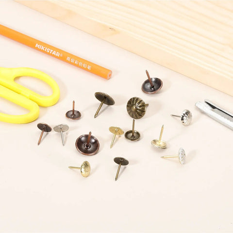 Fifty Pack Vintage Flower Head Upholstery Tacks Iron Metal Furniture Repair Nails Decorative Crafting Supplies For Couch Chairs Diy Home Projects Gold White Finish Hella Durable Top Notch Quality For Easy Fix Ups Crib Refresh And Quick Nail Setup, assorted decorative tacks on a table.