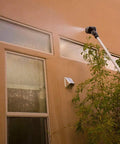 Using a 2-Pack Telescoping Watering Tool With Five-Position Pole Extending From 3.5 To 6 Feet, spraying high windows.