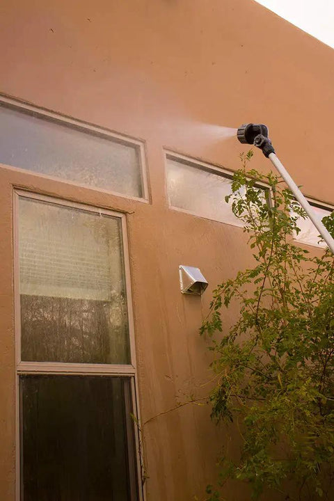 Using a 2-Pack Telescoping Watering Tool With Five-Position Pole Extending From 3.5 To 6 Feet, spraying high windows.
