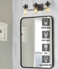 Three Light Farmhouse Vanity Light Fixture in oil rubbed bronze above mirror showing light bulb options, clear glass shades.