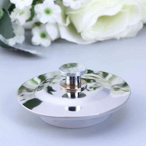Drain Stopper Flat Cover 40-45mm Stainless Steel for Bathtub resting beside white flowers on a light surface.