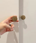 Hand holding knob from Antique Brass Cabinet Knob Set 6 Pack Solid Zinc Alloy Drawer Pulls for Kitchen Cabinets and Dressers