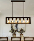 Farmhouse Style 6 Light Black Metal Industrial Pendant Lighting For Dining Room And Kitchen Island Vintage Rectangular Linear Chandelier with bulbs showcased over a dining table.