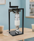Top Shelf Manual Jar Sealer For 55Mm Soda Pots With Heavy Steel Build and Smooth Rotary Winder on a wooden table with drinks.