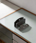 Heavy Duty Frameless Glass Door Hinge And Zinc Alloy Cabinet Clamps For 8 Millimeter Panels Smooth Glide displayed on glass surface.