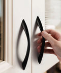Person installing 5 Inch Arch Twisted Matte Black Cabinet Pulls For Kitchen Drawers And Cabinets, Heavy Duty Zinc Alloy Hardware