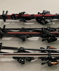 Three pairs of black and red skis with bindings, laid out parallel on a flat surface, ready for use in winter sports