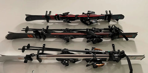 Three pairs of black and red skis with bindings, laid out parallel on a flat surface, ready for use in winter sports
