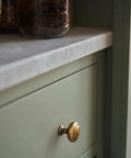 Real Deal Antique Brass Cabinet Knobs 1 1/4 Inch Round Sunburst Design on green cabinet drawer.