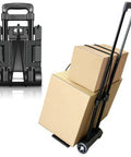 Black folding hand truck luggage cart with two wheels and straps, carrying two cardboard boxes