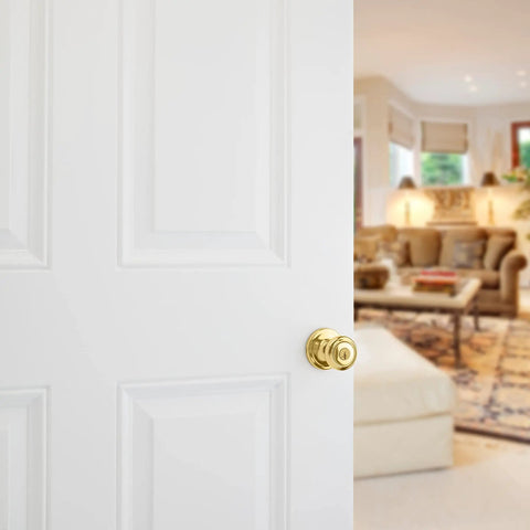 Cameron Entry Door Knob With Lock And Key, Polished Brass Finish, on white door in a cozy living room setting