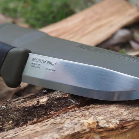 Companion Carbon Steel Fixed Blade Knife With Sheath 4.1 Inch Blade Military Green resting on wood