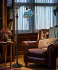 Dope Tiffany Style Stained Glass Floor Lamp With Sea Blue Dragonfly Pattern, 62 Inch Tall Industrial Dark Bronze Pole, 11 Inch Wide Shade, Ideal Reading Lamp For Living Room, Bedroom, Office Or Study next to leather armchair in cozy room