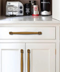 10 Pack Center To Center Three And A Half Inch Antique Brass Cabinet Pulls installed on white kitchen cabinets and drawer.