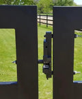 Two Way Gate Latch System Kit Black Finish Built Tough With Stainless Latch Pin Plate Helps Stop Gate Lean Corrosion Free Weatherproof Farm Fence Hardware For Barns And Fences So You Can Open It From Either Side, installed on black aluminum gate in grassy field.