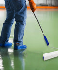 Worker using 9 Inch Spiked Roller For Self Leveling Screeds And Epoxy Floors Pro Grade Bubble Removal Tool on green floor